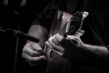 A man plays the guitar in front of a microphone